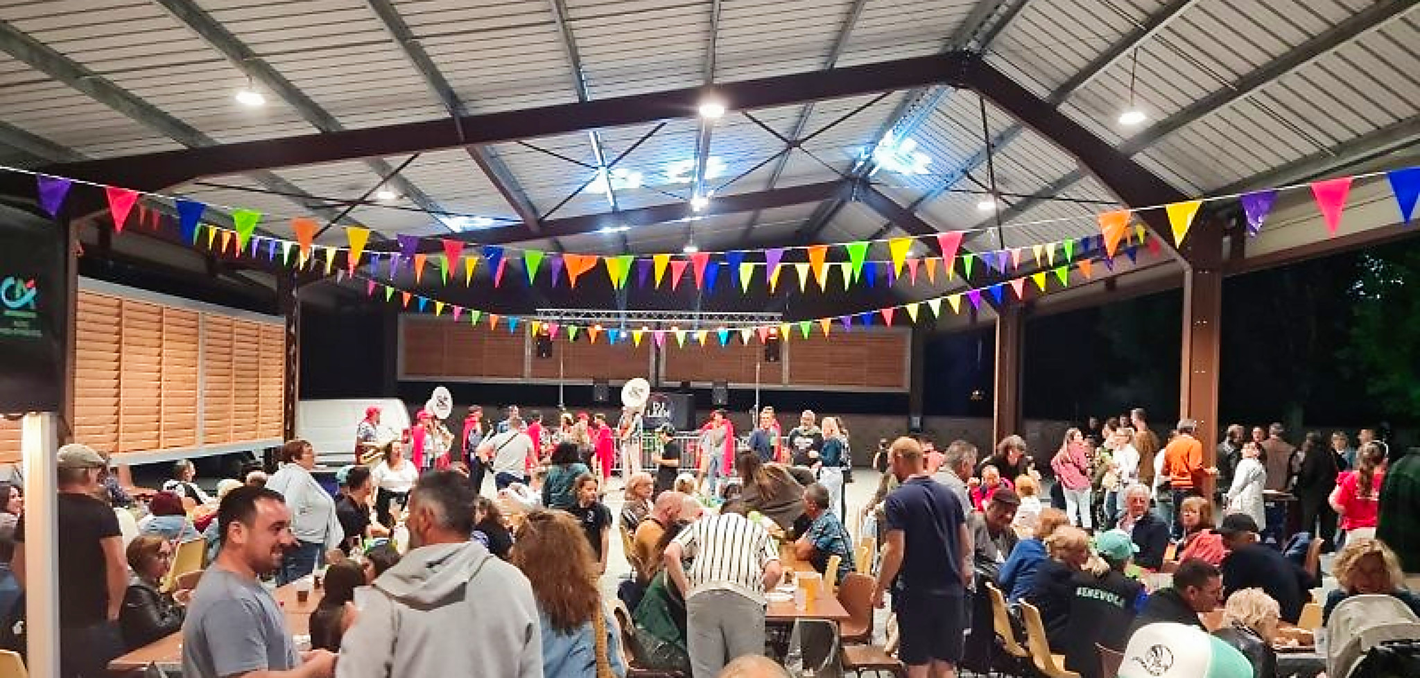Une halle remplie de monde avec des bandas au fond 
